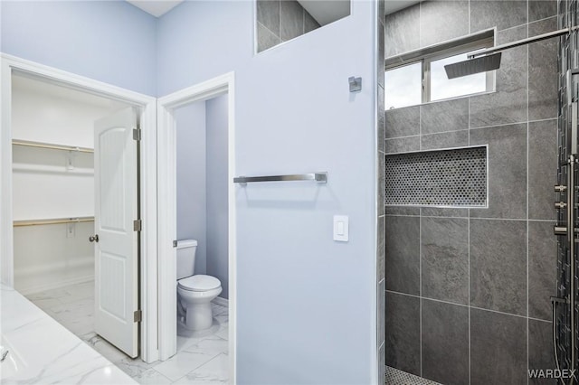 full bath featuring a walk in closet, marble finish floor, toilet, and a walk in shower