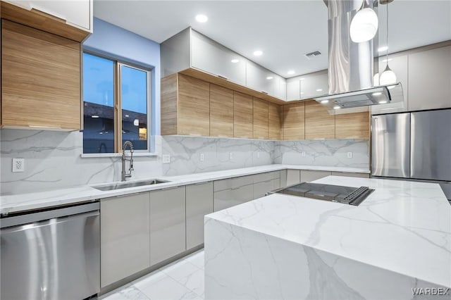 kitchen with modern cabinets, appliances with stainless steel finishes, hanging light fixtures, light stone countertops, and a sink