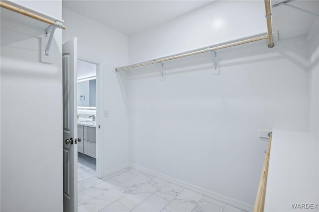 spacious closet with marble finish floor and a sink