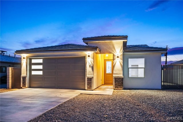 prairie-style home featuring driveway, a tiled roof, an attached garage, fence, and stucco siding