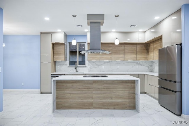 kitchen featuring light countertops, island exhaust hood, freestanding refrigerator, and decorative light fixtures