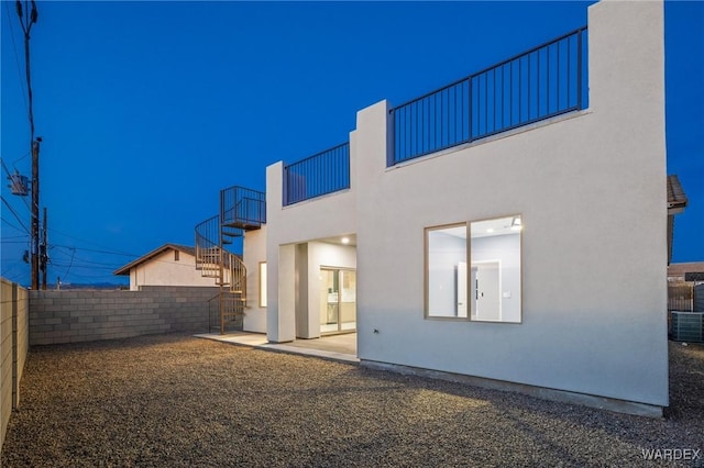 back of property featuring stairs, fence, and stucco siding