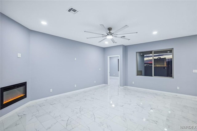 empty room with ceiling fan, visible vents, baseboards, marble finish floor, and a glass covered fireplace