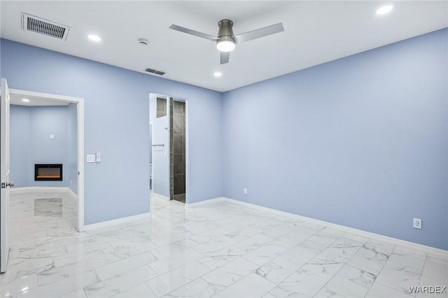 unfurnished bedroom with marble finish floor, baseboards, visible vents, and a glass covered fireplace