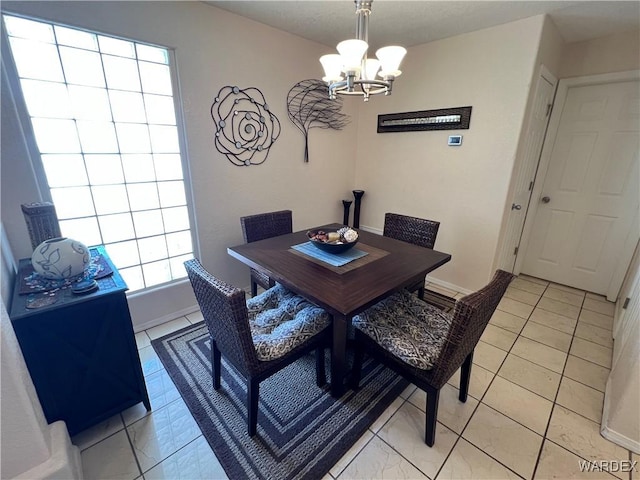 dining space with light tile patterned floors, baseboards, and a notable chandelier