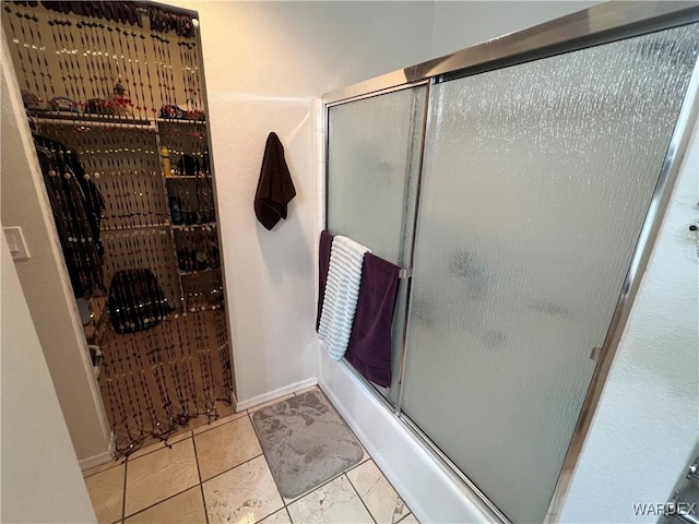 full bath featuring baseboards and a shower with shower door