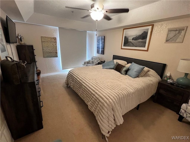 carpeted bedroom featuring a raised ceiling, ceiling fan, and visible vents