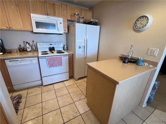 kitchen featuring light countertops, a textured wall, and white appliances