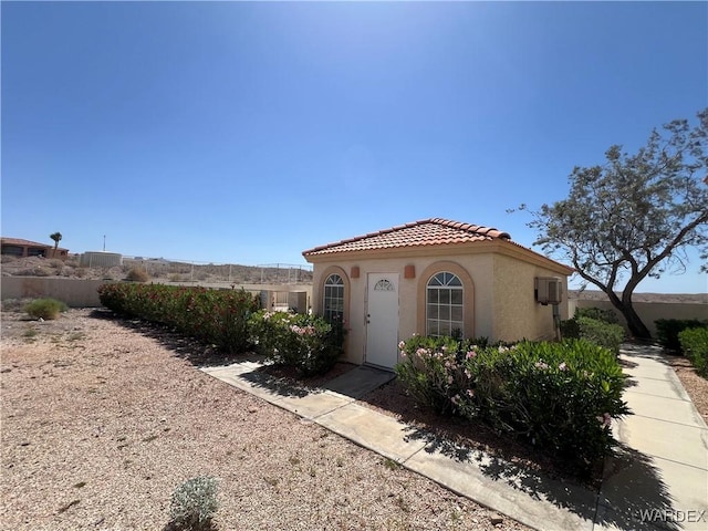 mediterranean / spanish house with fence, stucco siding, and a tile roof
