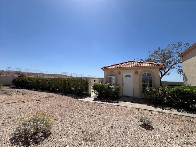 mediterranean / spanish-style home with stucco siding, a tile roof, and fence