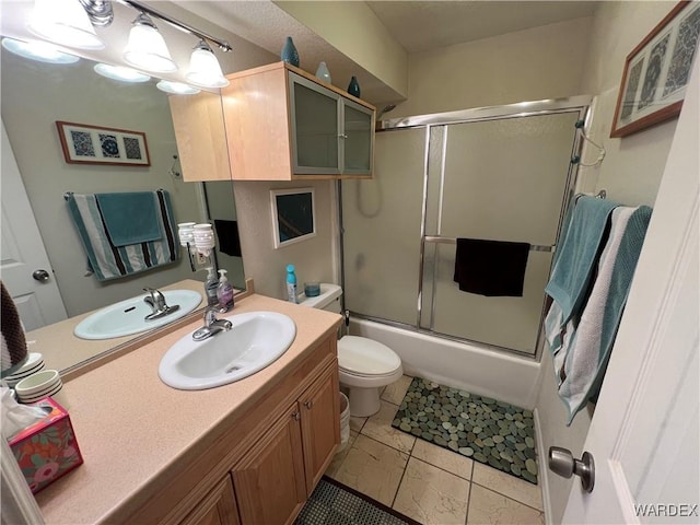 bathroom featuring vanity, combined bath / shower with glass door, and toilet