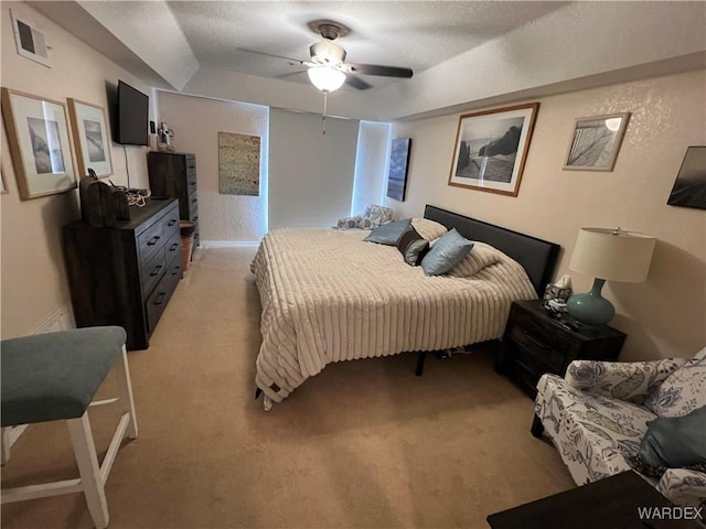 bedroom featuring visible vents, a ceiling fan, light colored carpet, and a raised ceiling