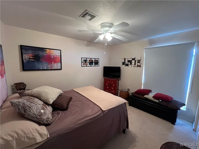 bedroom with visible vents, a ceiling fan, a textured ceiling, and light colored carpet