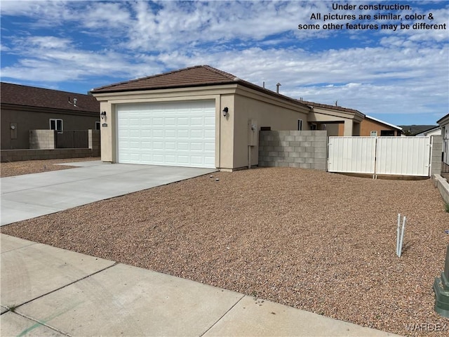 exterior space featuring a garage, driveway, fence, and stucco siding