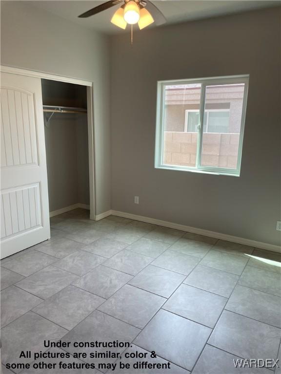 unfurnished bedroom featuring a closet, light tile patterned flooring, a ceiling fan, and baseboards