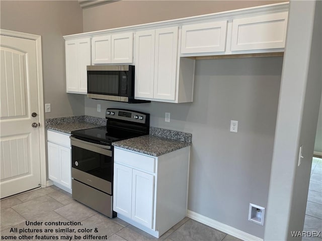 kitchen featuring white cabinetry, stainless steel appliances, and dark stone counters