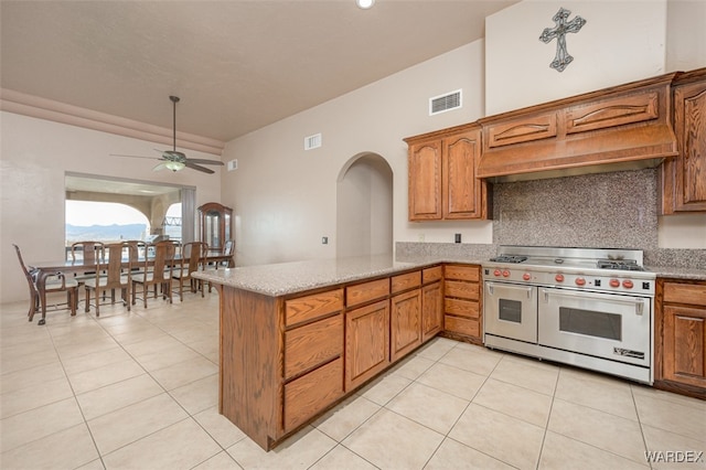 kitchen featuring range with two ovens, visible vents, brown cabinets, and a peninsula