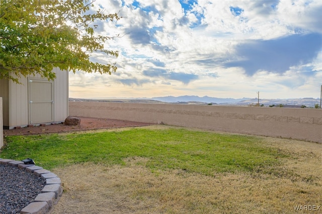 view of yard with a mountain view, a storage shed, and fence