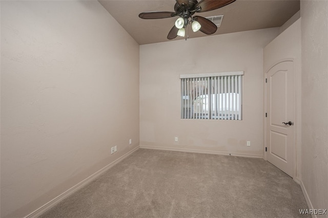 spare room featuring light carpet, a ceiling fan, visible vents, and baseboards