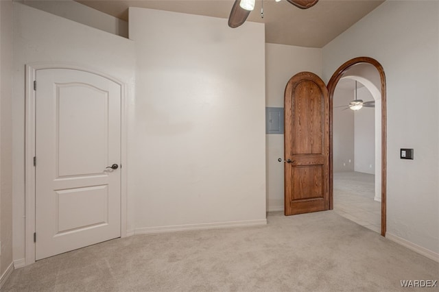 spare room featuring arched walkways, a ceiling fan, and light colored carpet