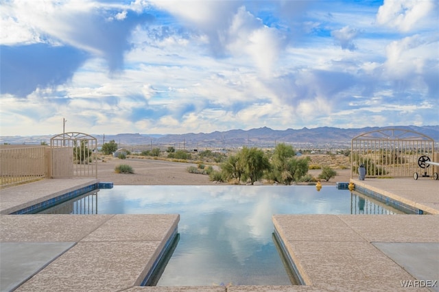 pool featuring a patio, fence, and a mountain view