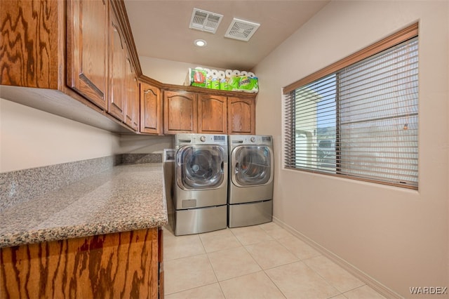 clothes washing area with cabinet space, light tile patterned flooring, visible vents, and independent washer and dryer