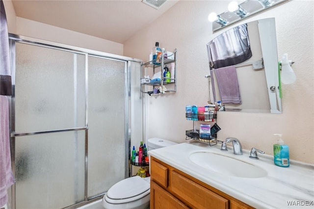 bathroom with visible vents, a stall shower, vanity, and toilet