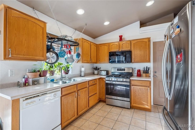 kitchen featuring stainless steel appliances, lofted ceiling, light countertops, light tile patterned flooring, and a sink