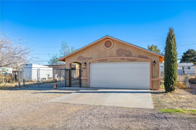 view of front of house featuring a gate, driveway, fence, and stucco siding