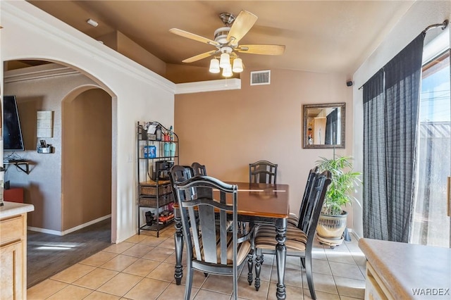 dining space featuring arched walkways, ceiling fan, light tile patterned flooring, visible vents, and vaulted ceiling