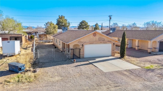 single story home with concrete driveway, an attached garage, a gate, fence, and stucco siding