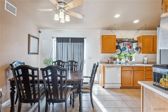 kitchen with light tile patterned floors, light countertops, visible vents, white dishwasher, and a sink