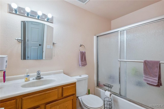 bathroom featuring toilet, bath / shower combo with glass door, and vanity