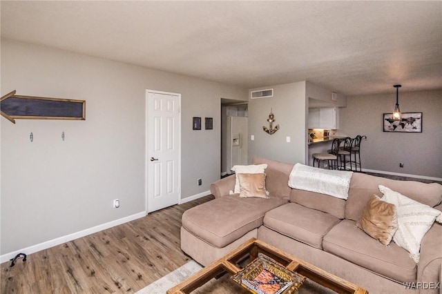 living room with baseboards, visible vents, and light wood-style floors