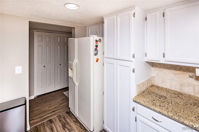 kitchen with white fridge with ice dispenser, white cabinetry, dark wood finished floors, and light stone counters