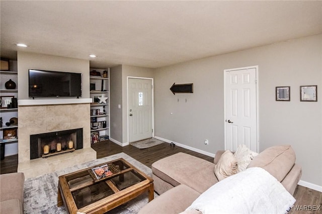 living area with a tile fireplace, recessed lighting, wood finished floors, and baseboards