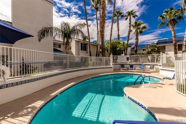 community pool with a patio area and fence