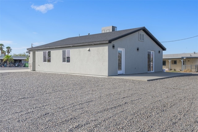 rear view of house featuring a patio area and stucco siding