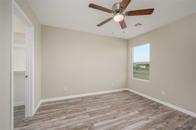 unfurnished room featuring light wood-style floors, baseboards, visible vents, and ceiling fan