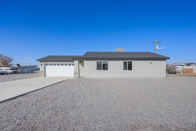 ranch-style house featuring driveway, an attached garage, and stucco siding