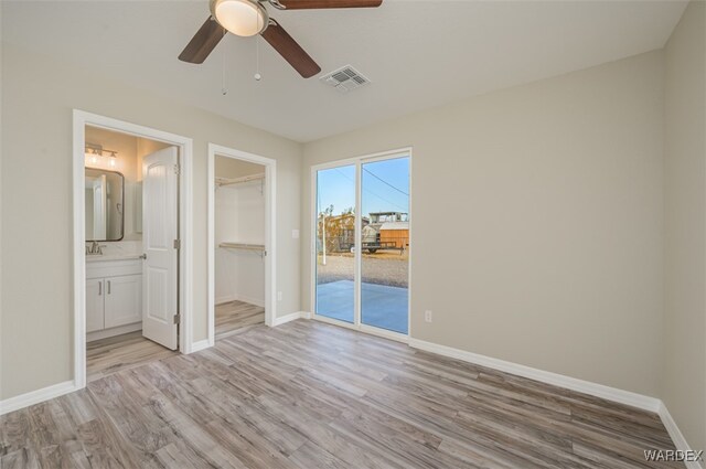 unfurnished bedroom featuring baseboards, visible vents, access to exterior, a walk in closet, and light wood-type flooring