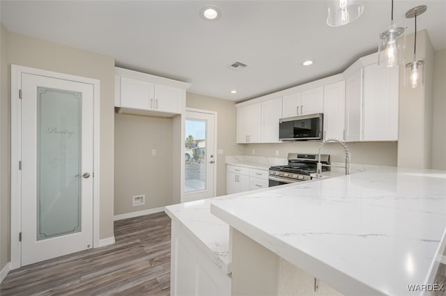 kitchen featuring white cabinetry, visible vents, pendant lighting, and stainless steel appliances