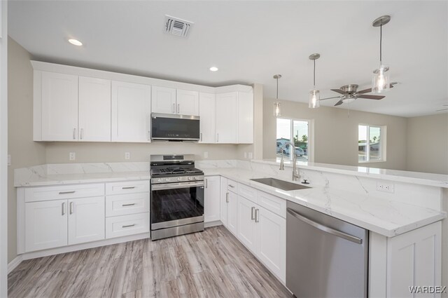 kitchen featuring a peninsula, appliances with stainless steel finishes, visible vents, and white cabinetry