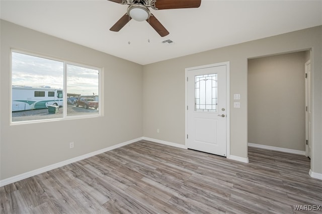 empty room with baseboards, light wood-type flooring, visible vents, and a healthy amount of sunlight