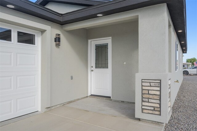 entrance to property featuring a garage and stucco siding