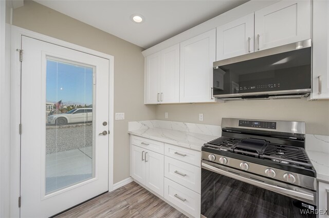 kitchen featuring recessed lighting, light wood-style flooring, appliances with stainless steel finishes, white cabinets, and light stone countertops