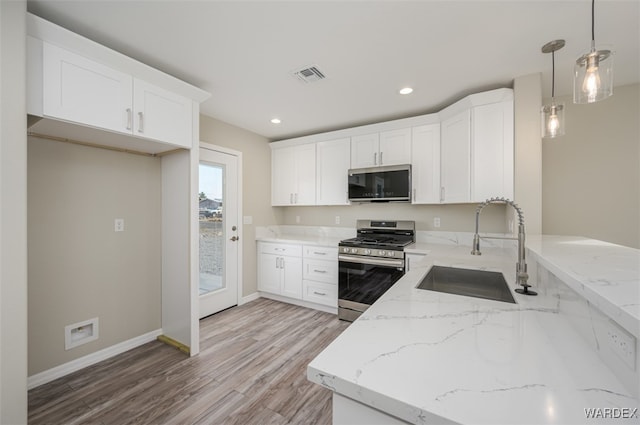 kitchen with visible vents, hanging light fixtures, appliances with stainless steel finishes, white cabinets, and a sink