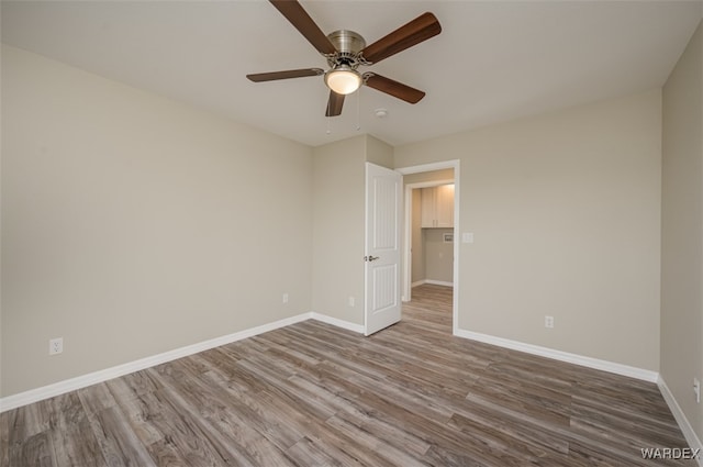 spare room featuring wood finished floors, a ceiling fan, and baseboards