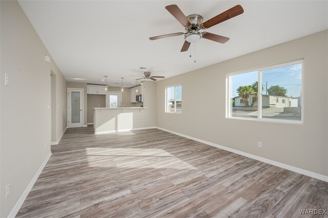 unfurnished living room with a healthy amount of sunlight, baseboards, and light wood finished floors