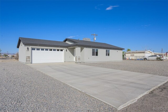 ranch-style house with driveway, an attached garage, and stucco siding